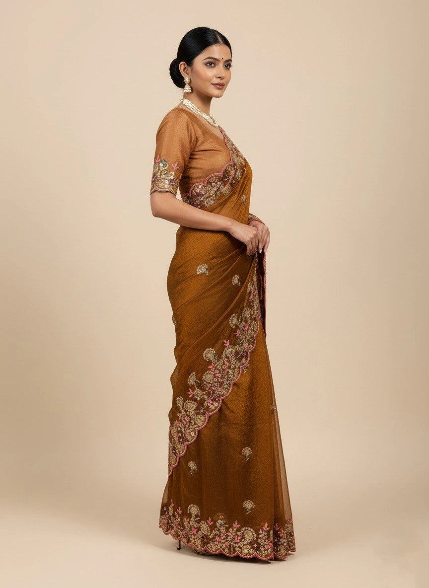 Woman wearing a brown saree with intricate patterns on a beige background